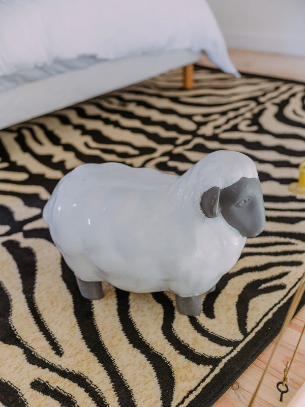 Mouton décoratif en céramique sur tapis zèbre dans l'appartement du Château de Laubardemont