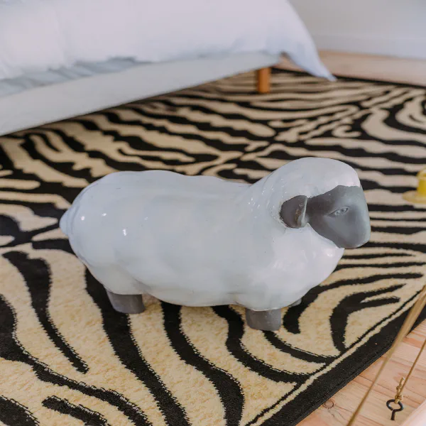 Mouton décoratif en céramique sur tapis zèbre dans l'appartement du Château de Laubardemont