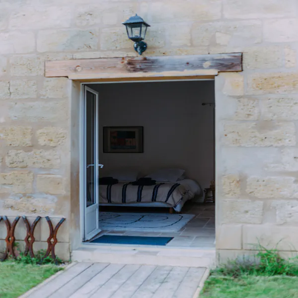 Façade en pierre blonde avec porte ouverte sur la chambre du gîte au château
