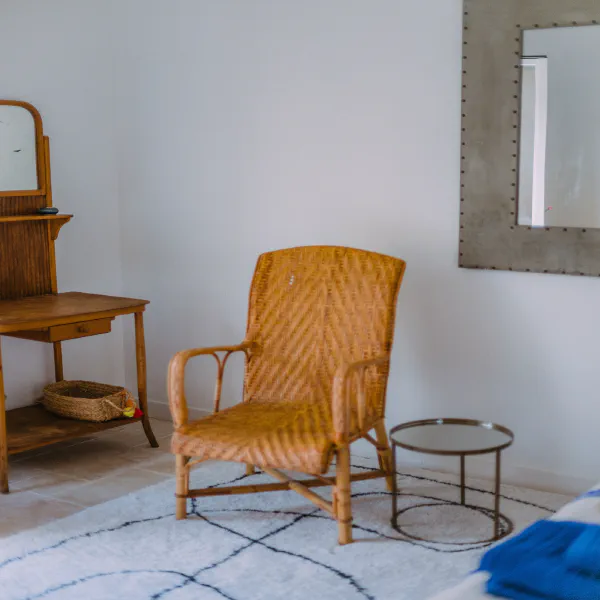 Fauteuil en rotin tressé et coiffeuse ancienne dans la chambre du gîte au château