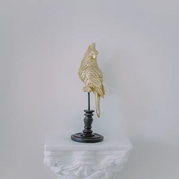 Statue de perroquet doré sur piédestal blanc, décoration du Château de Laubardemont