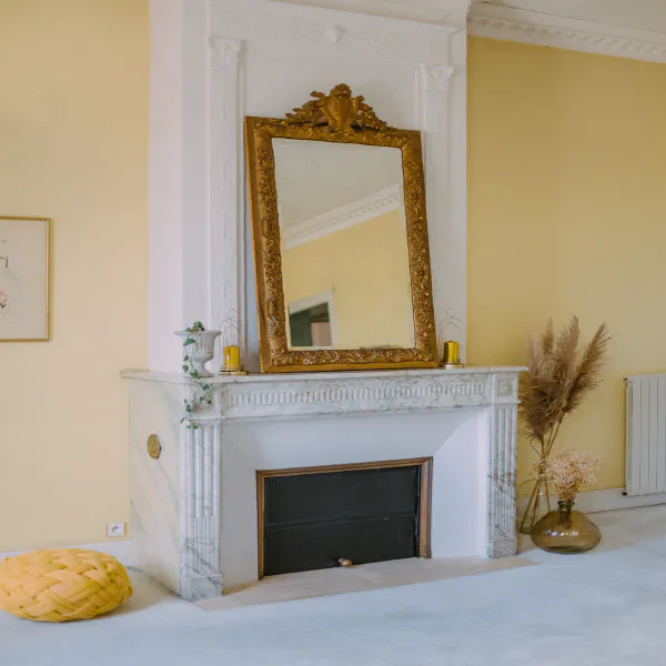 Cheminée en marbre avec grand miroir doré et fleurs séchées dans la chambre du château