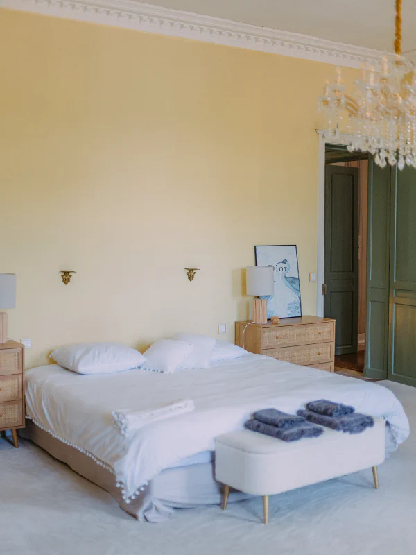 Chambre principale avec lit double, lustre cristal et portes vertes au Château de Laubardemont
