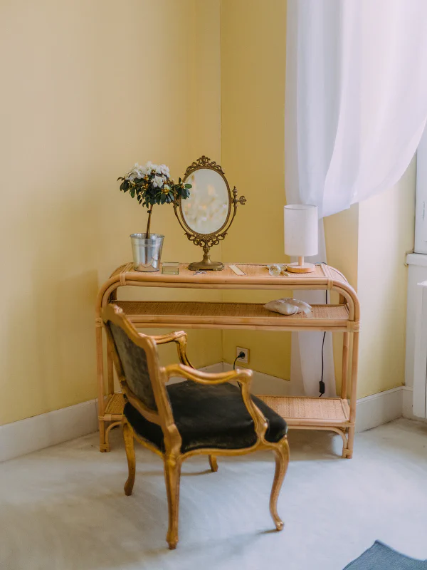 Coiffeuse en rotin avec miroir ancien et fauteuil Louis XV dans la chambre du château