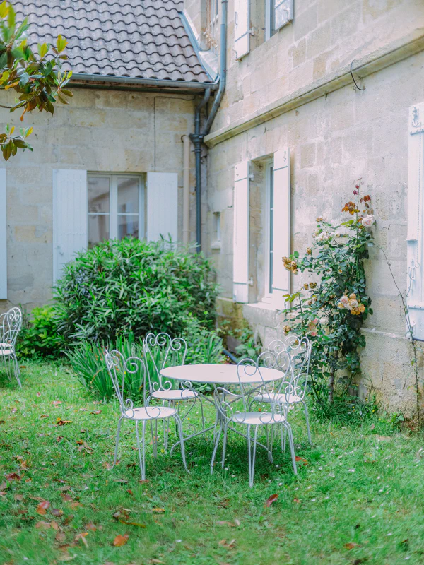 Table et chaises en fer forgé dans le jardin fleuri du Château de Laubardemont