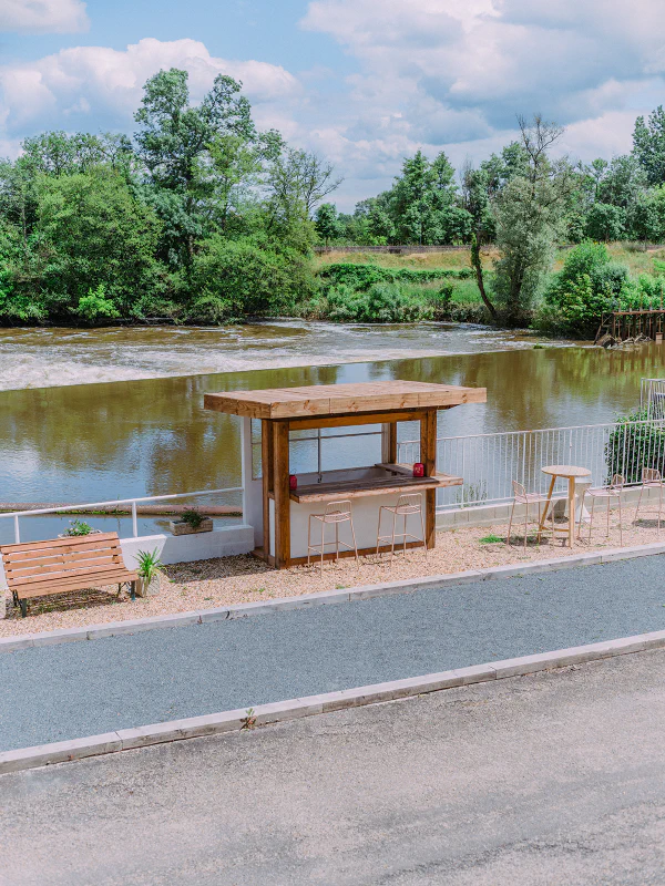 Bar extérieur en bois avec tabourets au bord de la rivière au Château de Laubardemont