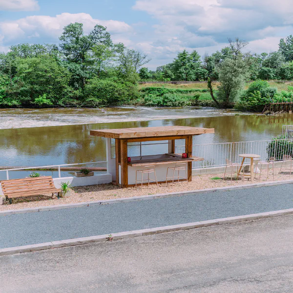 Bar extérieur en bois avec tabourets au bord de la rivière au Château de Laubardemont