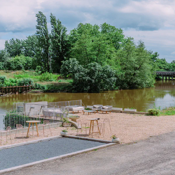 Terrasse avec salon lounge et terrain de pétanque au bord de la rivière au château