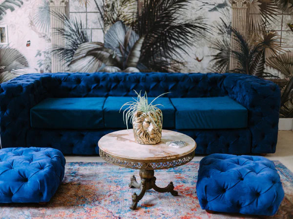 Canapé capitonné bleu velours, poufs et table en marbre du Château de Laubardemont