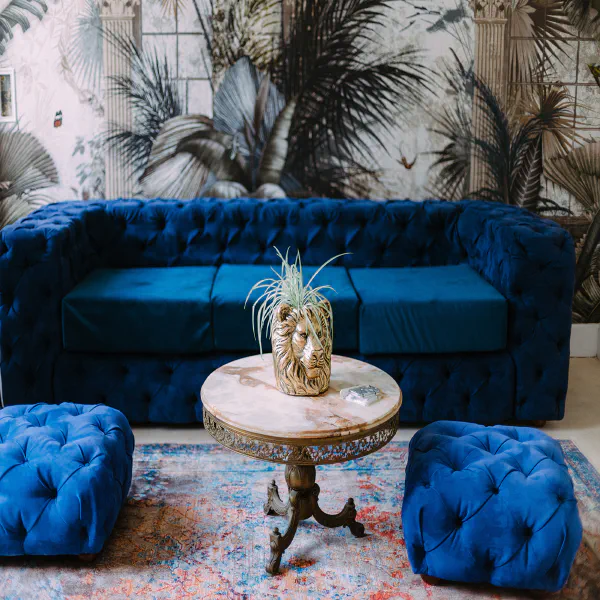 Canapé capitonné bleu velours, poufs et table en marbre du Château de Laubardemont