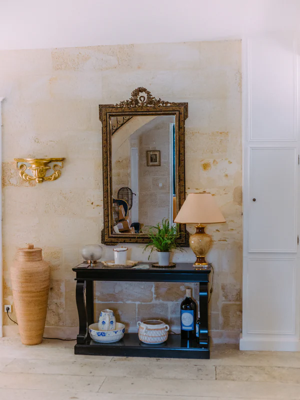 Miroir ancien orné sur mur en pierre avec console noire au Château de Laubardemont