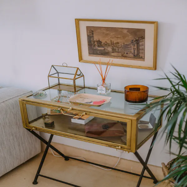 Table vitrine dorée avec bougie et gravure ancienne dans le salon du château